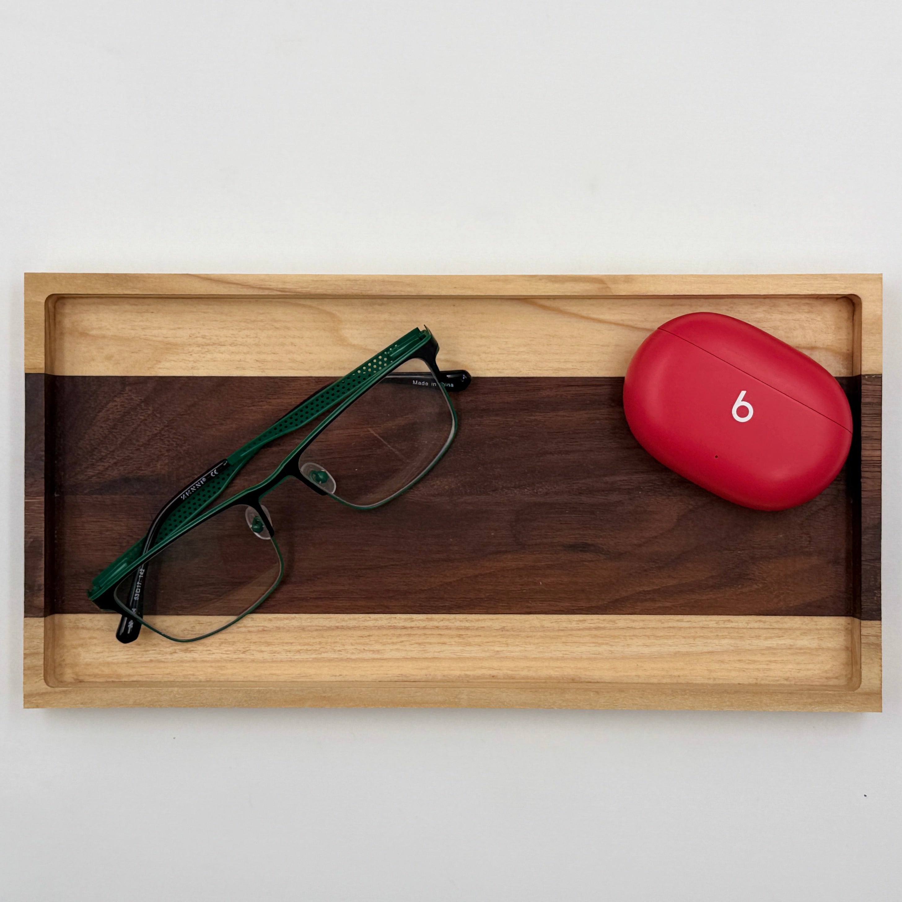Wooden tray with green eyeglasses and red case on a white background