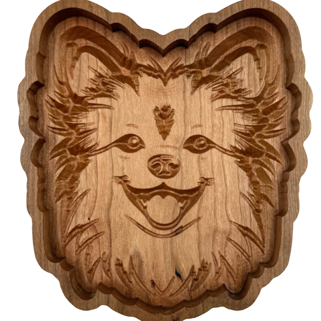 A carved wooden plaque or tray featuring a stylized dog face with detailed fur and a smiling expression, made from medium brown wood with visible grain.