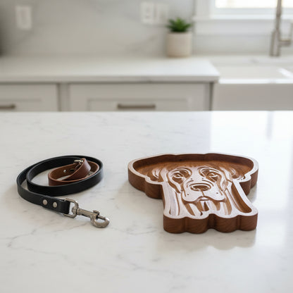 A carved wooden dog head tray or dish with a warm medium-brown wood grain, photographed from directly above on a plain white background.