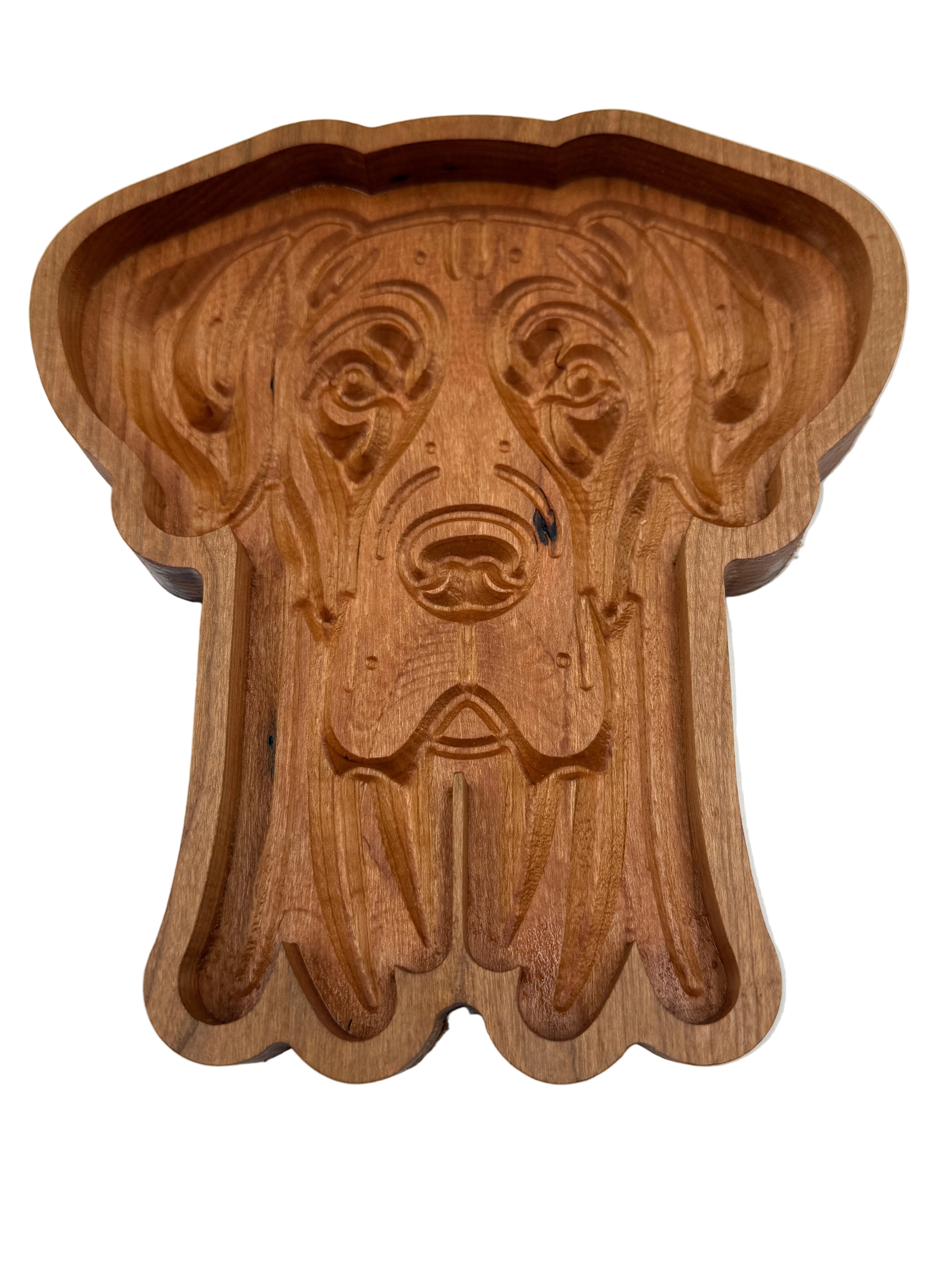 A carved wooden dog-shaped tray or dish with a warm medium-brown wood finish, photographed from above on a plain white background.