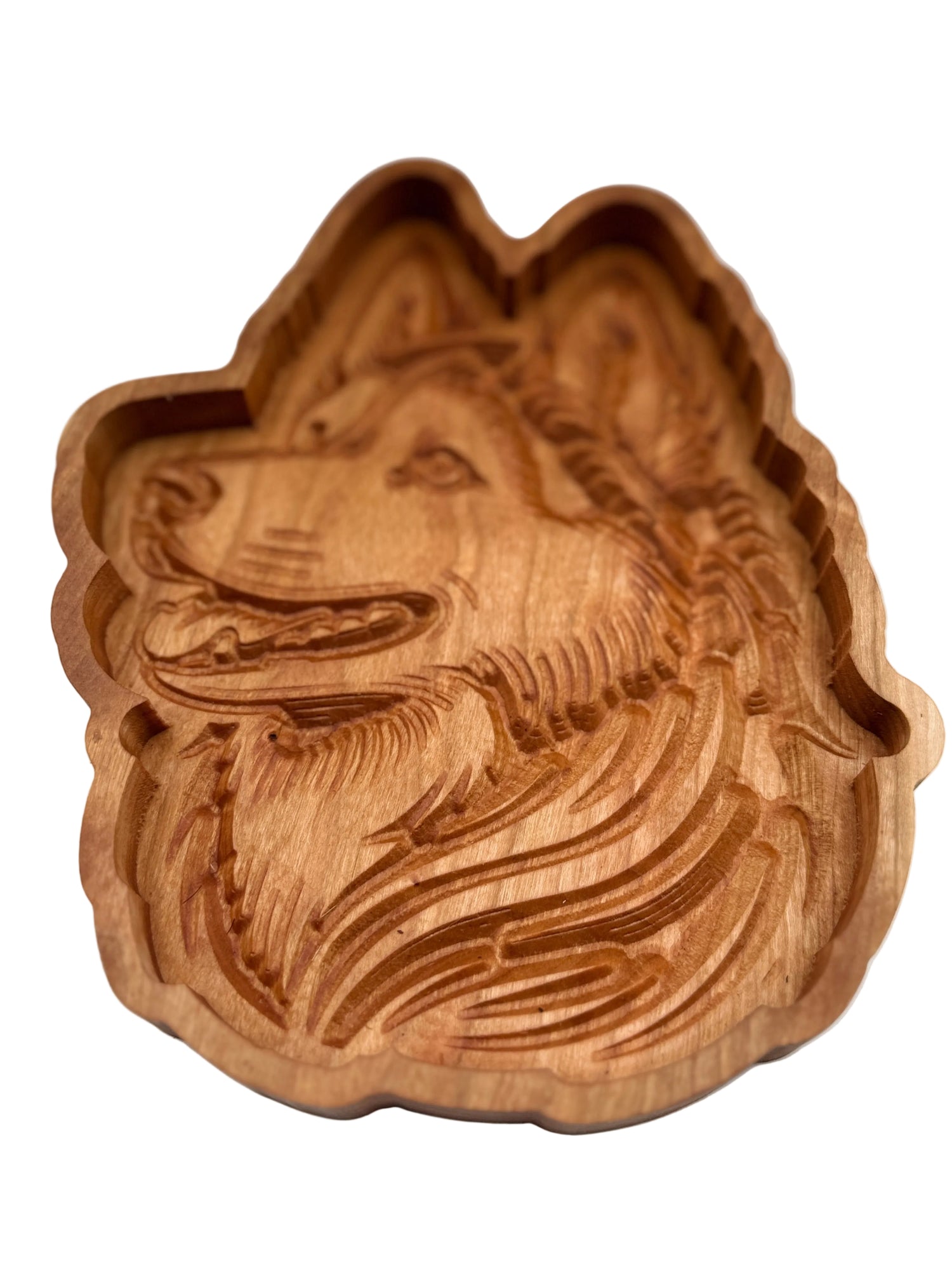 A carved wooden dog head plaque or tray with detailed wood grain and a smooth, slightly polished finish, set against a plain light gray background.