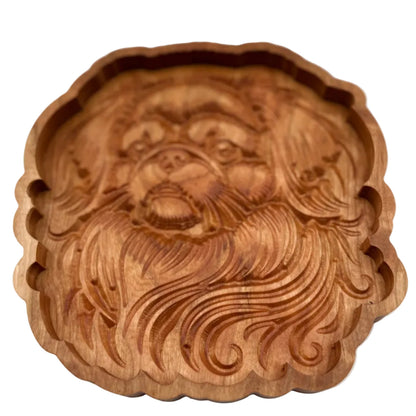 A round, hand-carved wooden decorative piece featuring a stylized face with flowing hair, shown against a plain light gray background.
