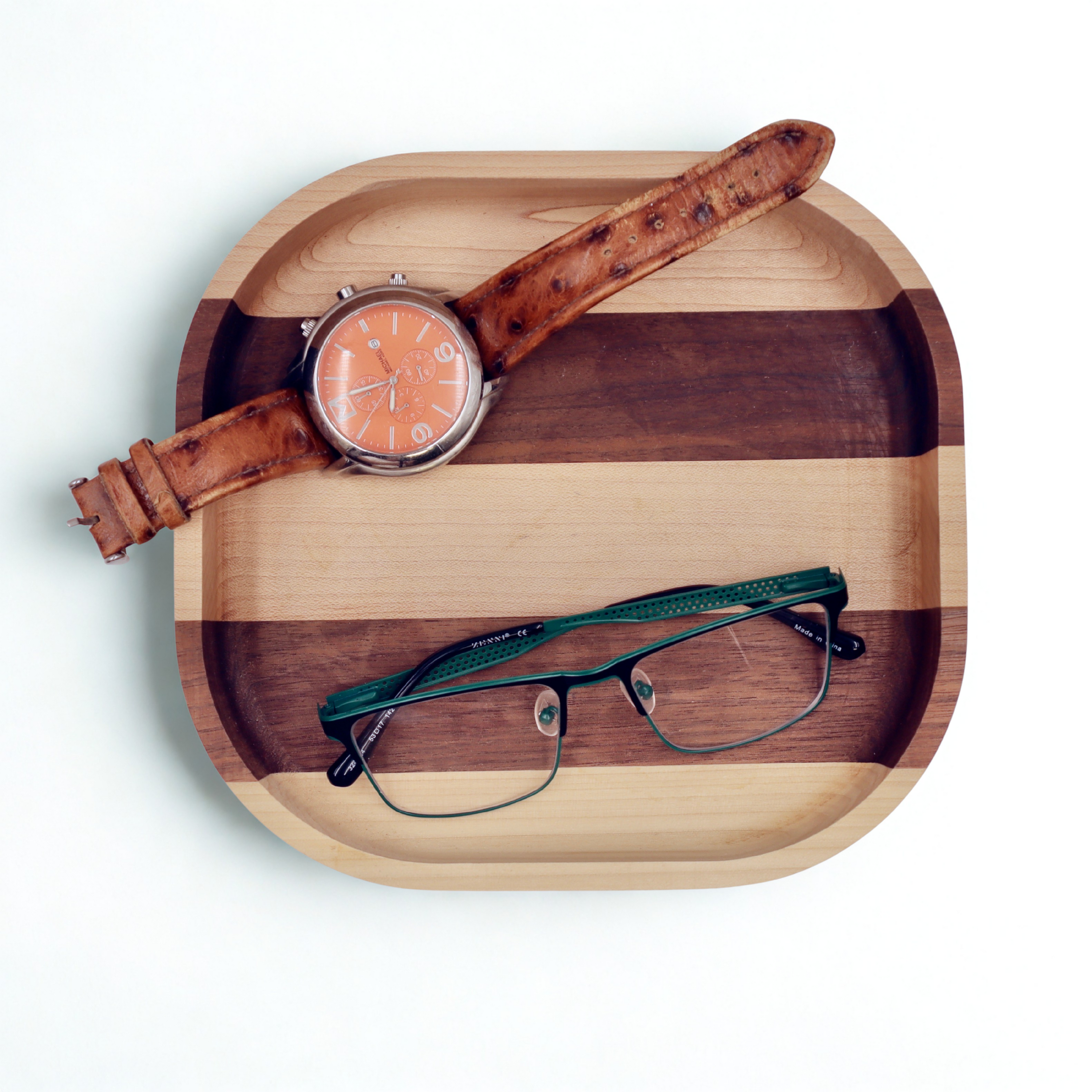 Wooden tray with a watch and eyeglasses on a white background